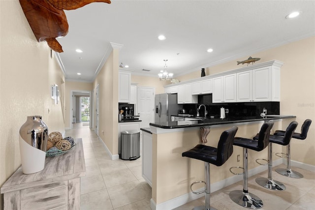300 Capri Blvd Unit 3, Treasure Island, FL 33706 - kitchen with stainless steel refrigerator with ice dispenser, a peninsula, crown molding, backsplash, and dark countertops