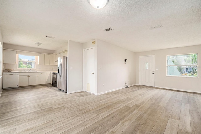 6131 17th St, Zephyrhills, FL 33542 - unfurnished living room with light wood-style floors and a textured ceiling