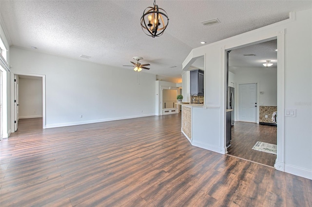 10505 Goldwater Ln, Riverview, FL 33578 - unfurnished living room with a textured ceiling, ceiling fan, dark wood-style flooring, and a chandelier