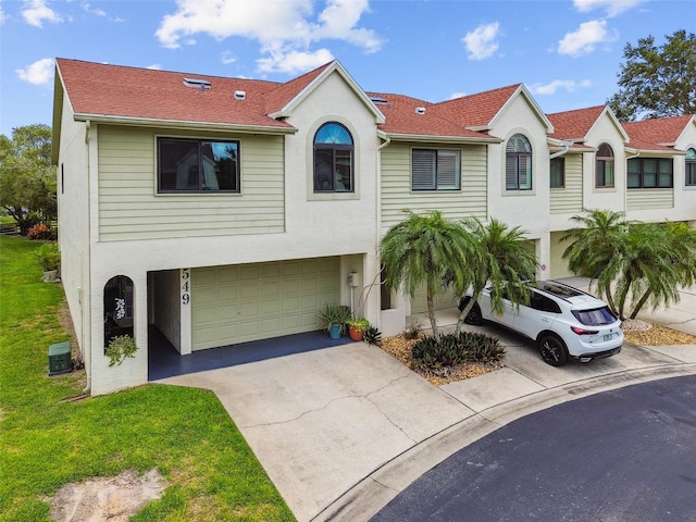 549 Walden Ct, Dunedin, FL 34698 - townhome / multi-family property featuring a garage, stucco siding, driveway, a shingled roof, and a front lawn