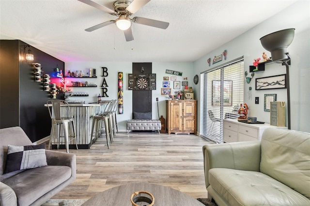 549 Walden Ct, Dunedin, FL 34698 - living room with bar, light wood-style flooring, ceiling fan, and a textured ceiling