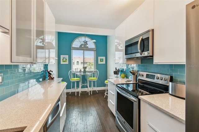 549 Walden Ct, Dunedin, FL 34698 - kitchen with stainless steel appliances, dark wood finished floors, white cabinets, light stone counters, and tasteful backsplash