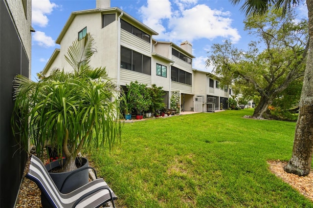 549 Walden Ct, Dunedin, FL 34698 - back of property featuring a chimney, a lawn, and stucco siding