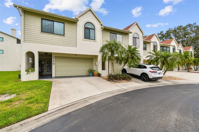 549 Walden Ct, Dunedin, FL 34698 - townhome / multi-family property with an attached garage, concrete driveway, stucco siding, a front lawn, and french doors