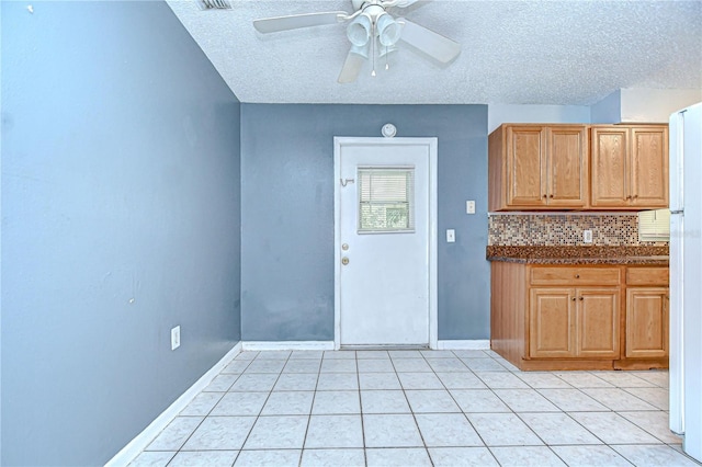 37740 Waverly Ave, Zephyrhills, FL 33542 - kitchen featuring a textured ceiling, dark countertops, a ceiling fan, light tile patterned floors, and decorative backsplash