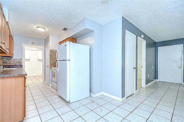 37740 Waverly Ave, Zephyrhills, FL 33542 - kitchen featuring freestanding refrigerator, light tile patterned flooring, a textured ceiling, range, and brown cabinets