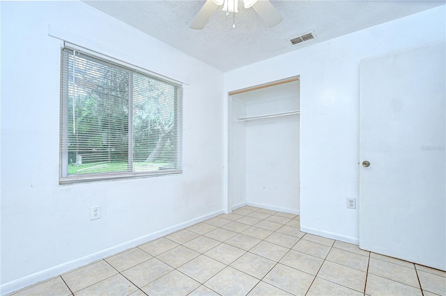 37740 Waverly Ave, Zephyrhills, FL 33542 - unfurnished bedroom with a textured ceiling, light tile patterned floors, a closet, and ceiling fan