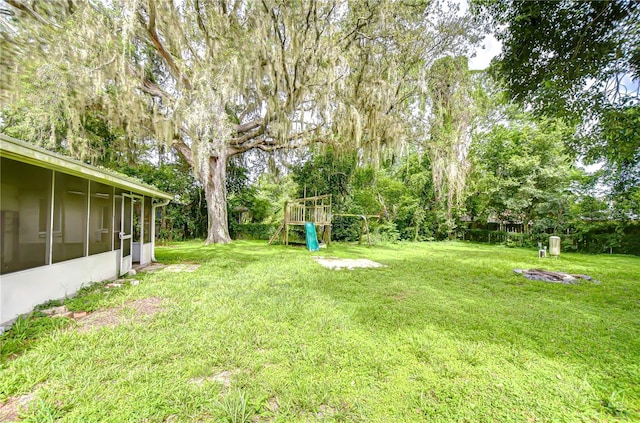 37740 Waverly Ave, Zephyrhills, FL 33542 - view of green lawn with a playground, a sunroom, and view of wooded area