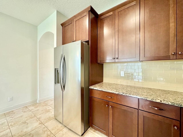 19502 Sea Myrtle Way, Tampa, FL 33647 - kitchen with stainless steel fridge, backsplash, light stone countertops, and a textured ceiling