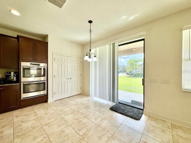19502 Sea Myrtle Way, Tampa, FL 33647 - kitchen with double oven, a chandelier, light tile patterned floors, pendant lighting, and a textured ceiling
