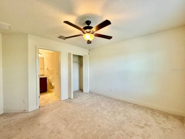 19502 Sea Myrtle Way, Tampa, FL 33647 - unfurnished bedroom with light carpet, a closet, connected bathroom, a ceiling fan, and a textured ceiling