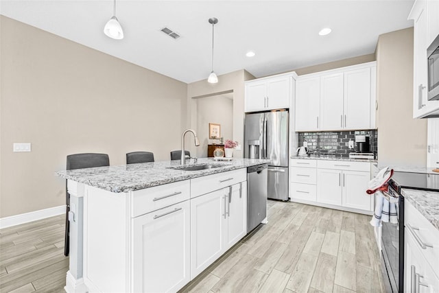 9237 Fox Sparrow Rd, Tampa, FL 33626 - kitchen with stainless steel appliances, light wood-style floors, decorative backsplash, a breakfast bar area, and an island with sink