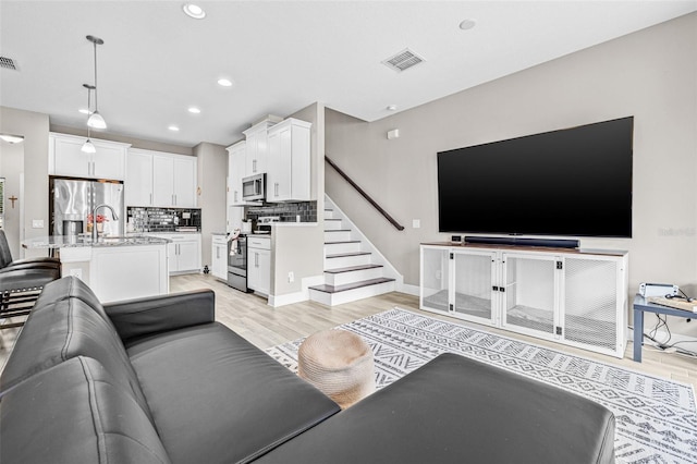 9237 Fox Sparrow Rd, Tampa, FL 33626 - living room with light wood finished floors, stairs, and recessed lighting