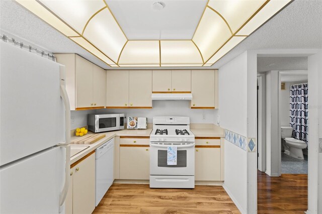 5920 80th St N Unit 308, Saint Petersburg, FL 33709 - kitchen with white appliances, under cabinet range hood, light countertops, light wood-type flooring, and cream cabinets