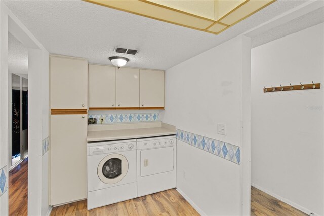 5920 80th St N Unit 308, Saint Petersburg, FL 33709 - laundry area featuring washing machine and dryer, light wood-type flooring, and a textured ceiling