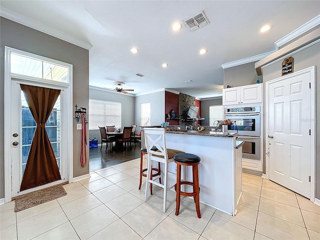 3108 Tom Matthews Rd, Lakeland, FL 33810 - kitchen with double oven, ornamental molding, a breakfast bar, white cabinetry, and a ceiling fan