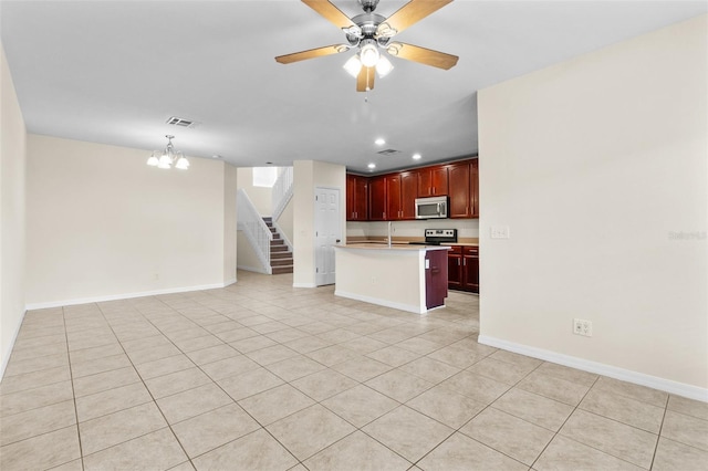 30151 Goodwick Way, Wesley Chapel, FL 33543 - kitchen featuring stainless steel microwave, open floor plan, dark brown cabinets, light tile patterned flooring, and light countertops