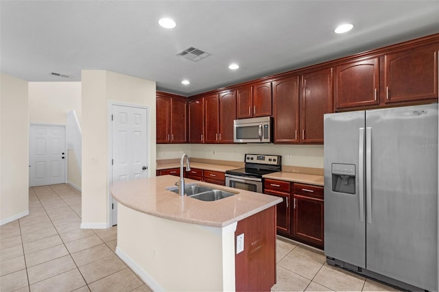 30151 Goodwick Way, Wesley Chapel, FL 33543 - kitchen featuring appliances with stainless steel finishes, light tile patterned floors, dark brown cabinets, a center island with sink, and light stone counters