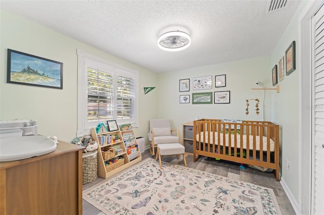 908 Toddsmill Trce, Tarpon Springs, FL 34689 - bedroom with wood finished floors, a textured ceiling, and a crib