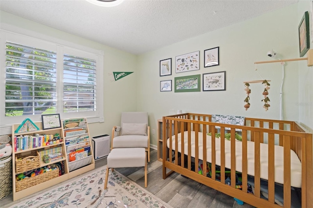 908 Toddsmill Trce, Tarpon Springs, FL 34689 - bedroom featuring wood finished floors, a textured ceiling, and a nursery area