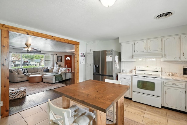 5628 Cypress St, Zephyrhills, FL 33542 - kitchen with white range with electric stovetop, stainless steel fridge with ice dispenser, light tile patterned flooring, light countertops, and ceiling fan