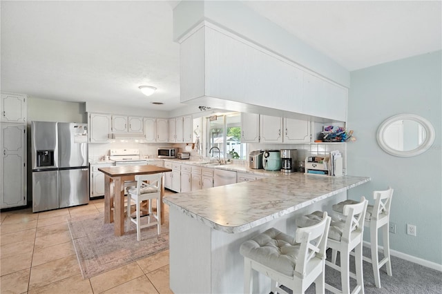 5628 Cypress St, Zephyrhills, FL 33542 - kitchen with stainless steel appliances, a peninsula, light countertops, a kitchen bar, and light tile patterned flooring