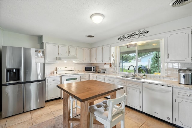 5628 Cypress St, Zephyrhills, FL 33542 - kitchen with stainless steel appliances, under cabinet range hood, backsplash, light countertops, and a textured ceiling