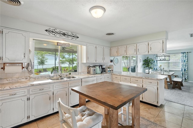 5628 Cypress St, Zephyrhills, FL 33542 - kitchen with a peninsula, dishwasher, healthy amount of natural light, light tile patterned flooring, and a textured ceiling