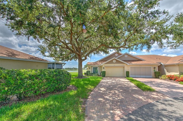 2012 Fall River Ct Unit 107, Sun City Center, FL 33573 - view of front of house featuring decorative driveway, a garage, and stucco siding