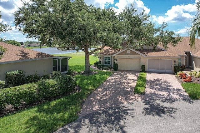 2012 Fall River Ct Unit 107, Sun City Center, FL 33573 - view of front of home with an attached garage, concrete driveway, a front lawn, and stucco siding
