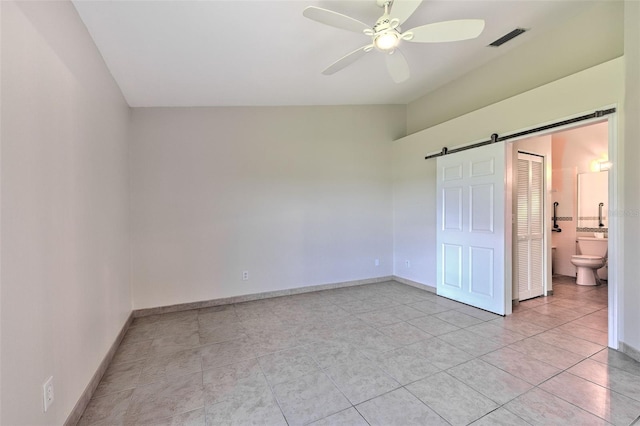 2012 Fall River Ct Unit 107, Sun City Center, FL 33573 - unfurnished bedroom with a barn door, light tile patterned flooring, ensuite bath, and a ceiling fan