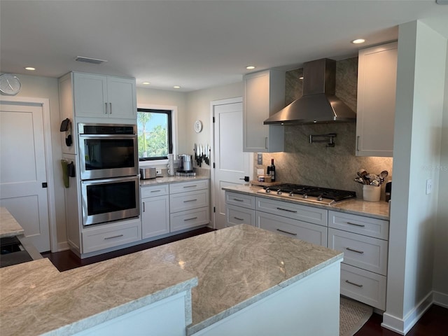 850 59th Ave, Saint Petersburg, FL 33706 - kitchen with wall chimney range hood, appliances with stainless steel finishes, light stone counters, decorative backsplash, and recessed lighting