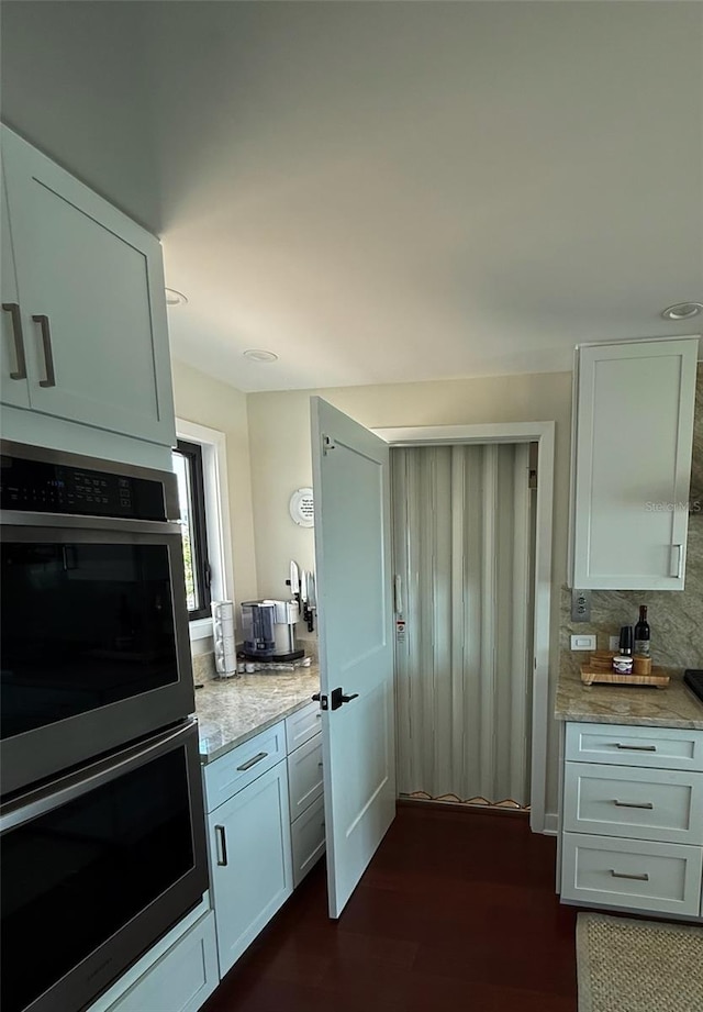 850 59th Ave, Saint Petersburg, FL 33706 - kitchen with double oven, light stone counters, dark wood-type flooring, white cabinetry, and decorative backsplash