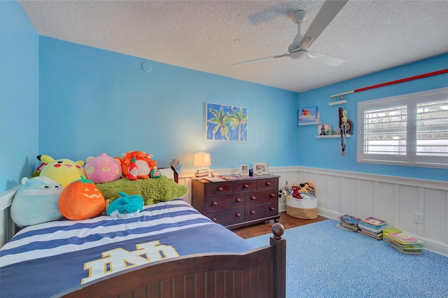 14 Evonaire Cir, Belleair, FL 33756 - bedroom with a textured ceiling, wainscoting, and a ceiling fan