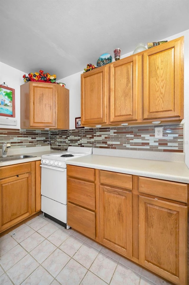 7740 Boca Ciega Dr Unit 204, St Pete Beach, FL 33706 - kitchen with white electric range, backsplash, light countertops, and light tile patterned floors