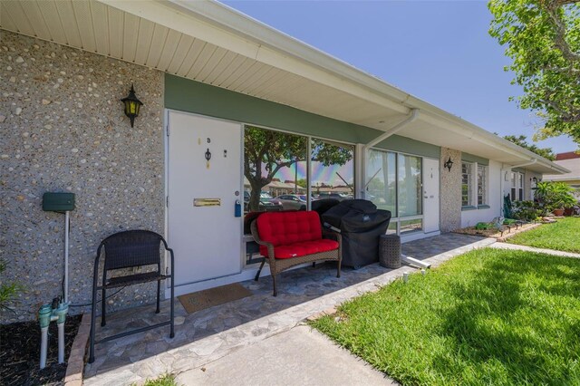 4357 Tahitian Gardens Cir Unit B, Holiday, FL 34691 - view of exterior entry featuring a patio, stucco siding, and a yard