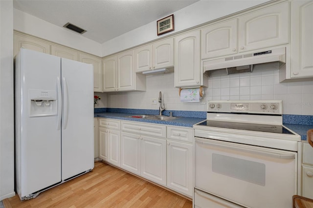 4357 Tahitian Gardens Cir Unit B, Holiday, FL 34691 - kitchen with white appliances, under cabinet range hood, dark countertops, light wood-style flooring, and decorative backsplash