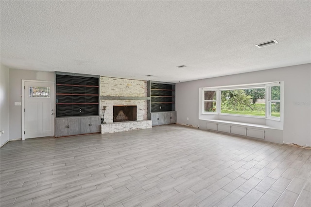 1712 Robin Hood Ln, Clearwater, FL 33764 - unfurnished living room featuring a textured ceiling, wood finished floors, and a brick fireplace