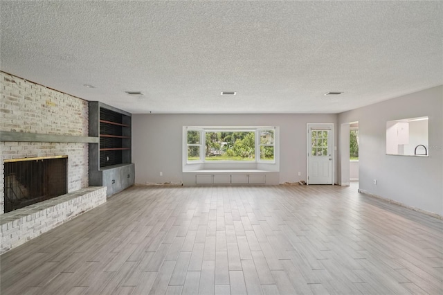 1712 Robin Hood Ln, Clearwater, FL 33764 - unfurnished living room with wood finished floors, a textured ceiling, a brick fireplace, and built in shelves