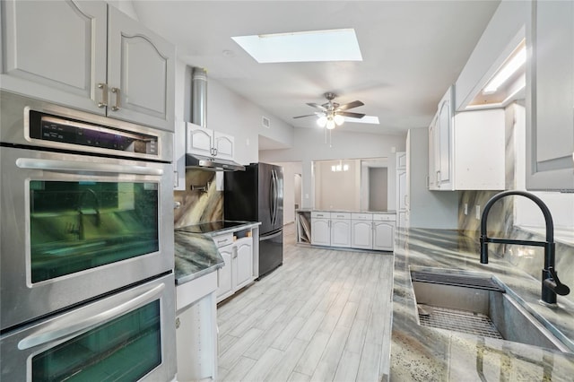1712 Robin Hood Ln, Clearwater, FL 33764 - kitchen with a skylight, appliances with stainless steel finishes, ceiling fan, under cabinet range hood, and light wood-style flooring