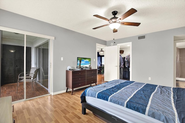250 Cypress Ln, Oldsmar, FL 34677 - bedroom with light wood-type flooring, a textured ceiling, ceiling fan, a walk in closet, and ensuite bath
