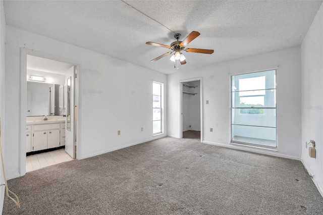 5245 Amulet Dr Unit 201, New Port Richey, FL 34652 - unfurnished bedroom with light colored carpet, a textured ceiling, connected bathroom, and a ceiling fan