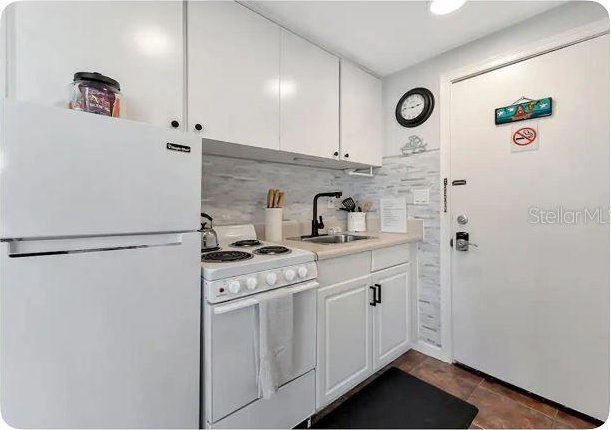 483 E Shore Dr Unit B4, Clearwater Beach, FL 33767 - kitchen with white appliances, white cabinetry, decorative backsplash, and light countertops