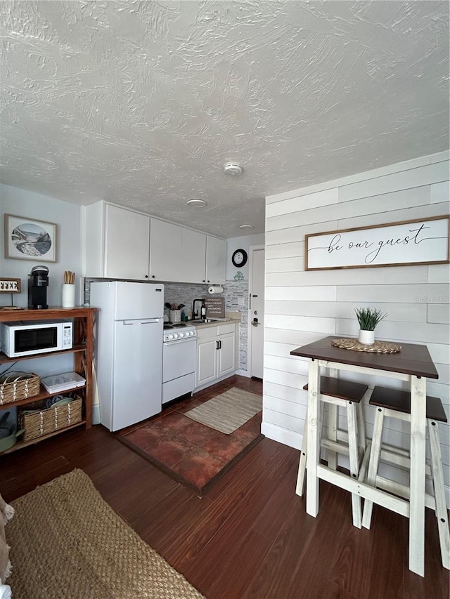 483 E Shore Dr Unit B4, Clearwater Beach, FL 33767 - kitchen featuring white appliances, dark wood finished floors, a textured ceiling, white cabinetry, and light countertops