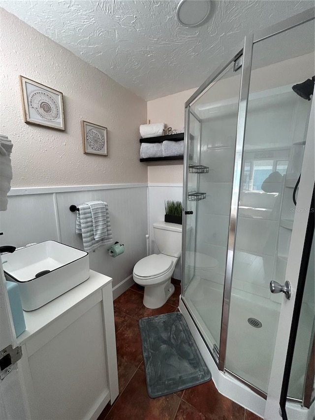 483 E Shore Dr Unit B4, Clearwater Beach, FL 33767 - bathroom featuring a textured ceiling, a stall shower, a wainscoted wall, tile patterned flooring, and a textured wall