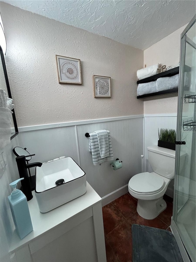 483 E Shore Dr Unit B4, Clearwater Beach, FL 33767 - bathroom with a shower stall, tile patterned floors, a textured ceiling, a wainscoted wall, and vanity