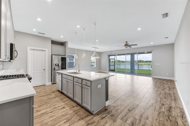 5434 Silver Sun Dr, Apollo Beach, FL 33572 - kitchen with gray cabinets, stainless steel appliances, open floor plan, light wood finished floors, and recessed lighting