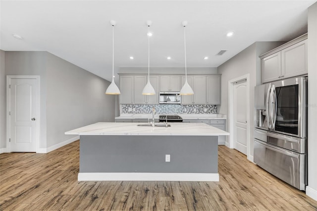 5434 Silver Sun Dr, Apollo Beach, FL 33572 - kitchen with stainless steel appliances, gray cabinetry, decorative backsplash, an island with sink, and light stone counters