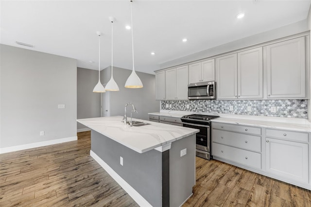 5434 Silver Sun Dr, Apollo Beach, FL 33572 - kitchen featuring stainless steel appliances, backsplash, light wood-style floors, a kitchen island with sink, and recessed lighting