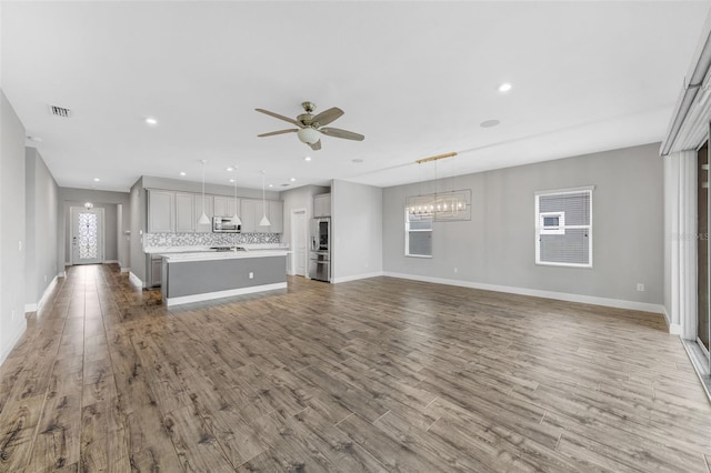 5434 Silver Sun Dr, Apollo Beach, FL 33572 - unfurnished living room with ceiling fan, healthy amount of natural light, a chandelier, wood finished floors, and recessed lighting
